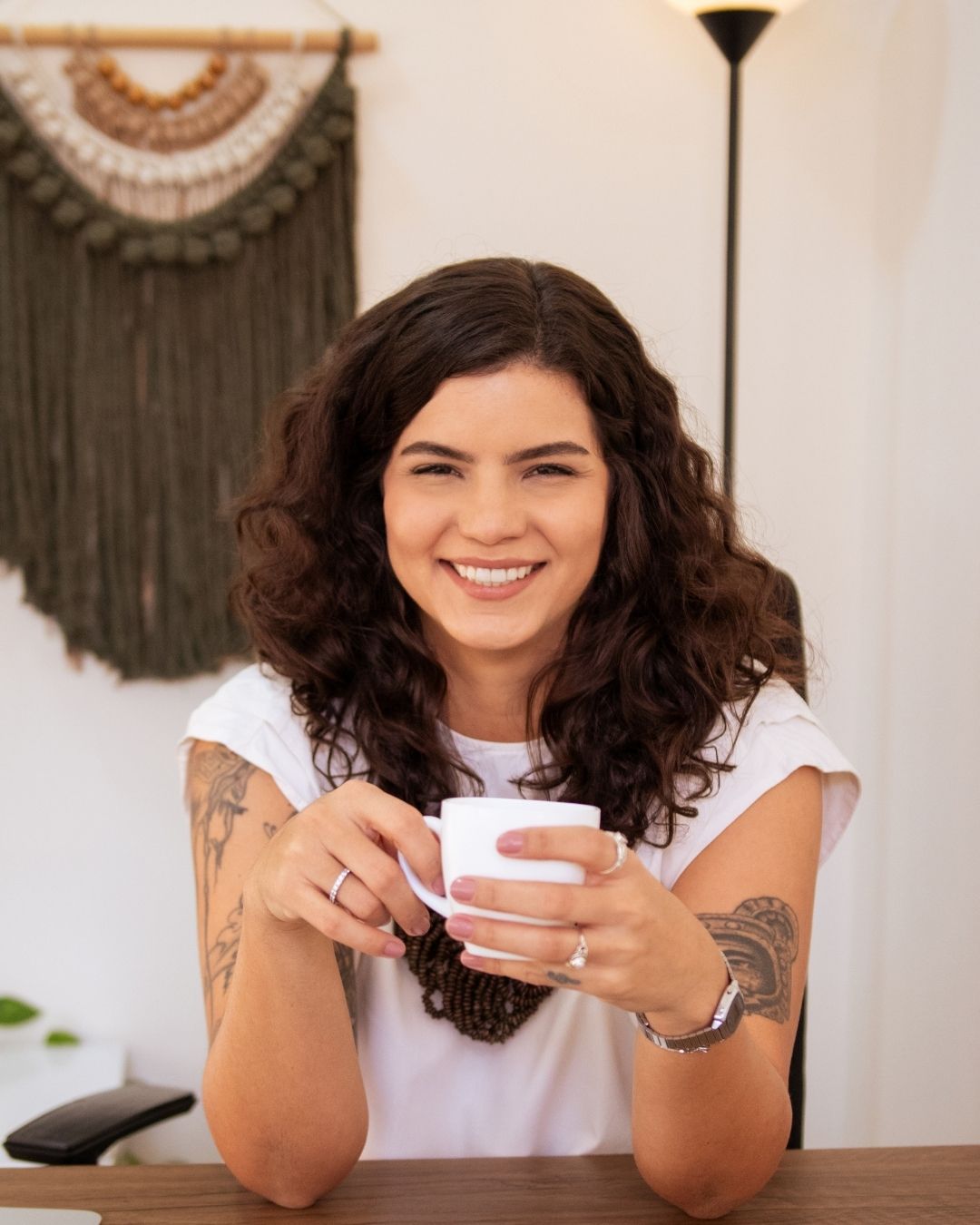 Caroline Leonel, psicóloga, sorrindo enquanto segura uma xícara de café